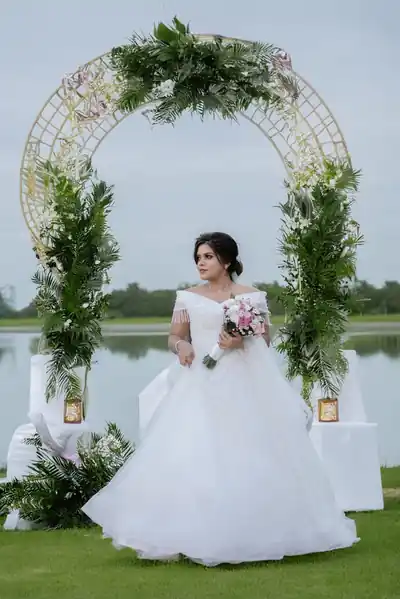 Bride in a white gown at a floral wedding arch